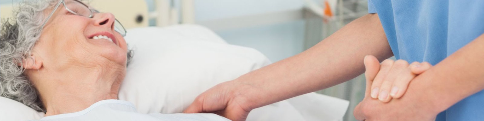 nurse checking on an elderly woman in a hospital bed